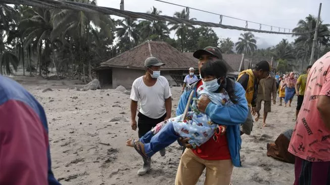 Warga berlarian di atas timbunan material guguran awan panas Gunung Semeru di Desa Sumber Wuluh, Lumajang, Jawa Timur, Minggu (5/12/2021). (Foto: ANTARA FOTO/Zabur Karuru)